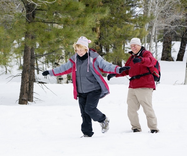 man and woman laughing, smiling, walking in snow