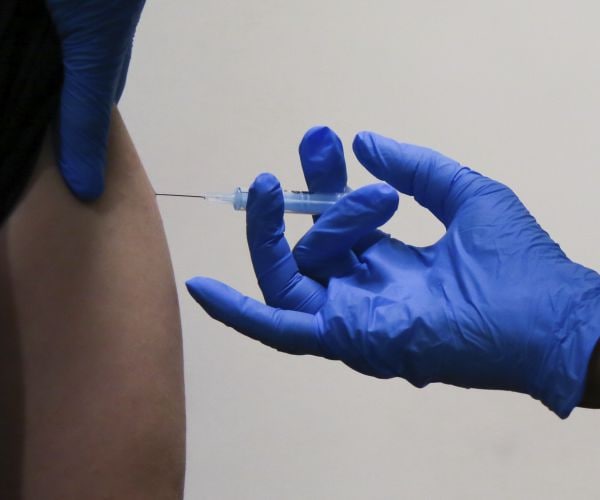 A health worker administers the Moderna COVID-19 booster vaccine to a woman at a vaccination center