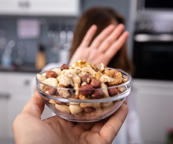 woman puts hand up to say 'no' to a bowl of nuts