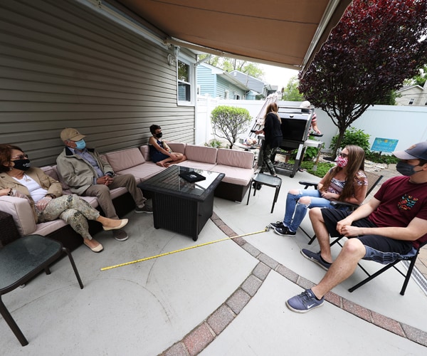 people sitting on couches wearing face masks and separated by a tape measure