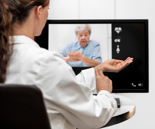 doctor in a white coat conducting a telehealth visit with an old woman