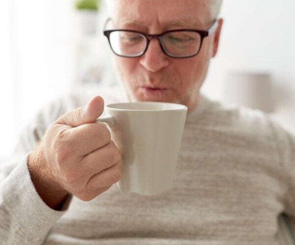 close up of older man drinking coffee from coffee cup