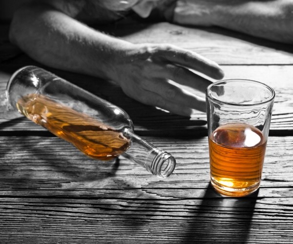 a half-bottle of brandy, glass of brandy, hand of a drunk person on table