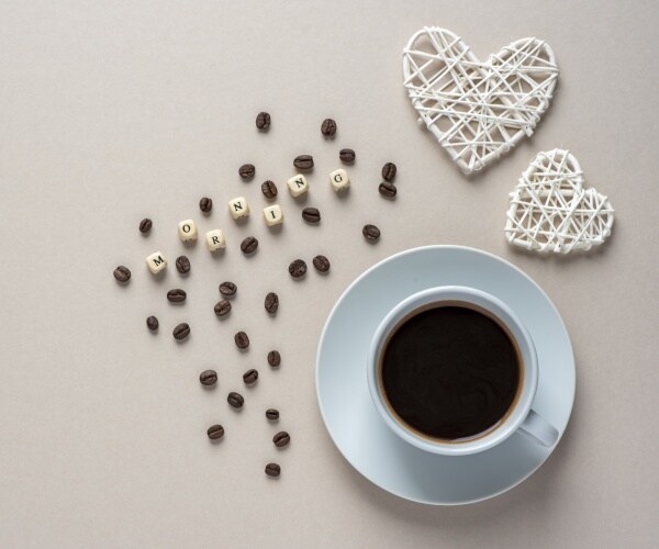 cup of coffee, with coffee beans and letters that spell coffee, and two hearts