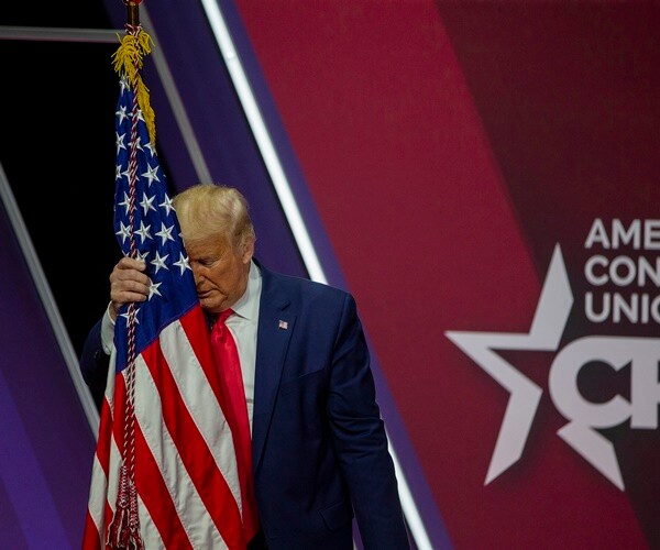 president donald trump puts his head on a flag