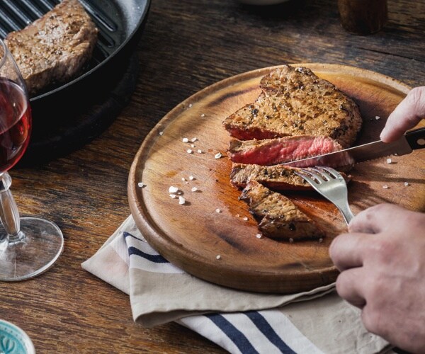 man cutting his steak with a knife