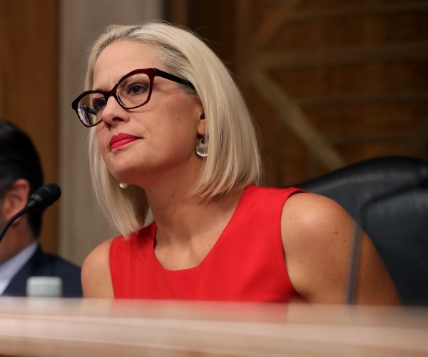 krysten sinema listens to a speaker