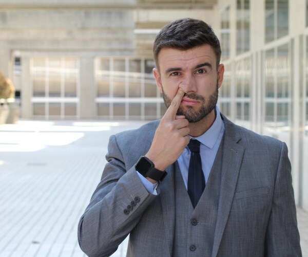 businessman in suit picking his nose