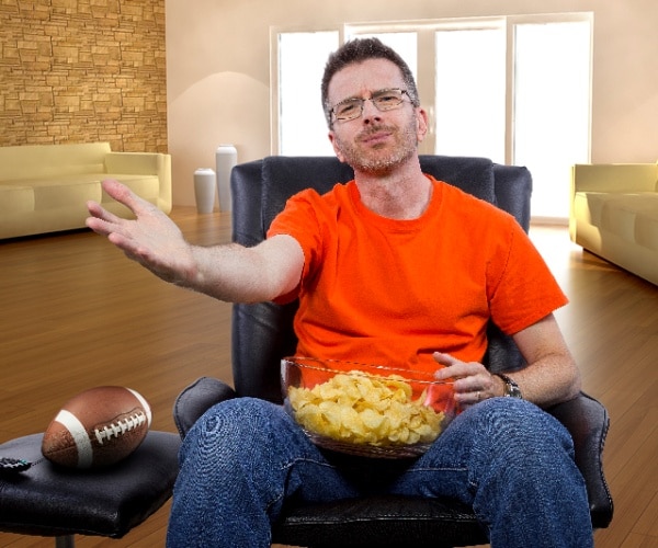 man in chair watching sports on tv, upset at team, with chips in his lap