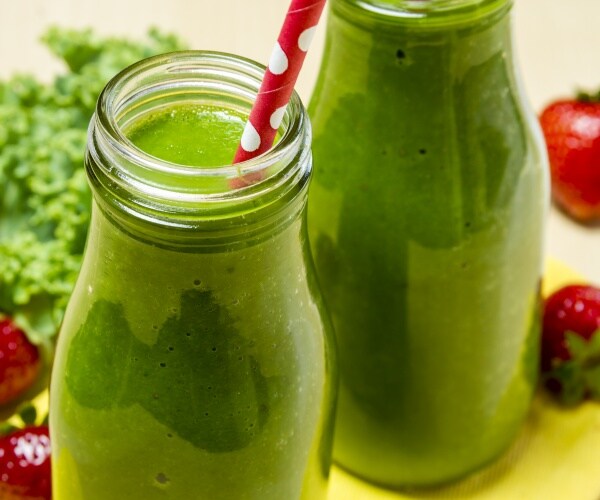 two green juice smoothies in glass bottles