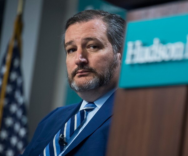 ted cruz listens next to a hudson institute podium