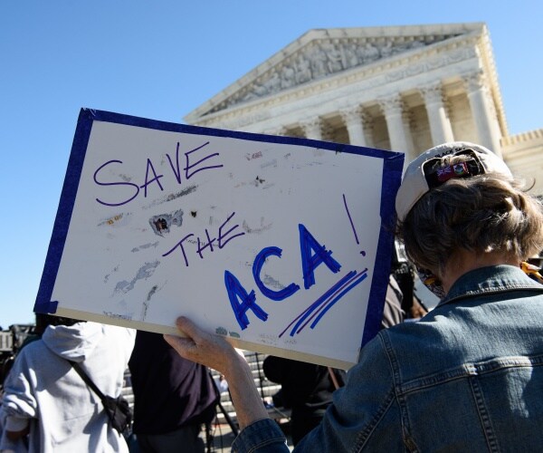 person holding sign that says 'SAVE ACA' during protest