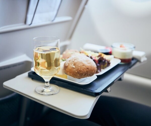 meal and glass of wine on airplane tray