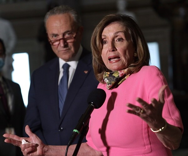 nancy pelosi speaks at a mic to the press with chuck schumer standing next to her.