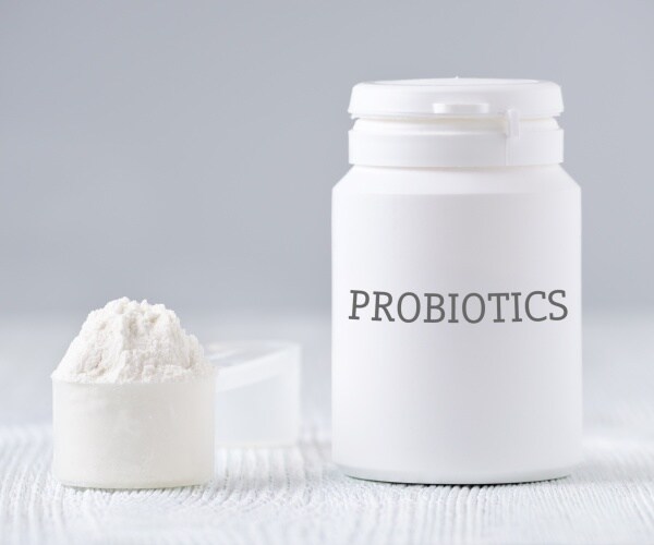 white container says 'probiotics' and a scoop and some powder on table