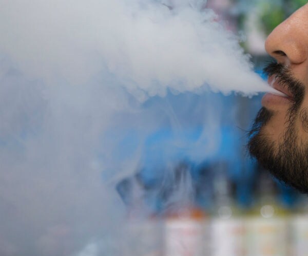 a man blows vapor after smoking an e cigarette