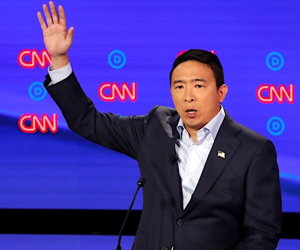 andrew yang raises his right hand during a democratic presidential primary debate