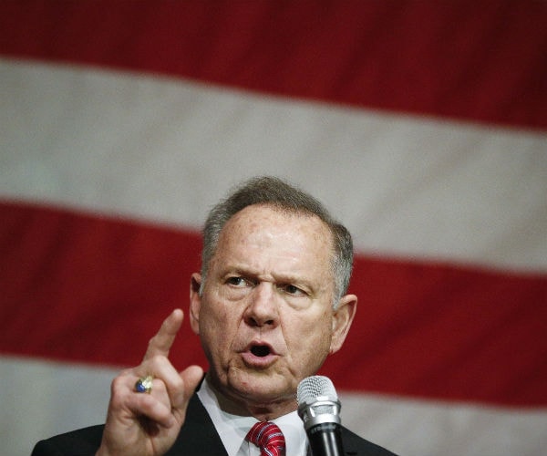 roy moore gestures as he speaks with the american flag in the background