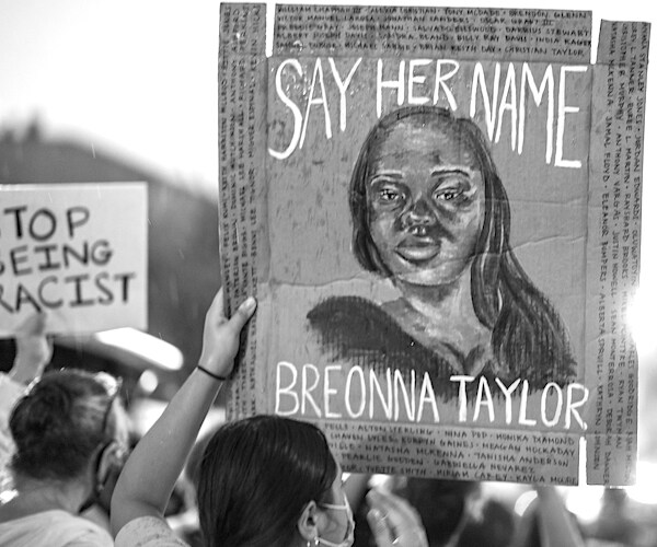 a protest holds up a breonna taylor say her name sign during a demonstration