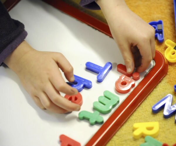 a child's hands are shown putting letters on a white board