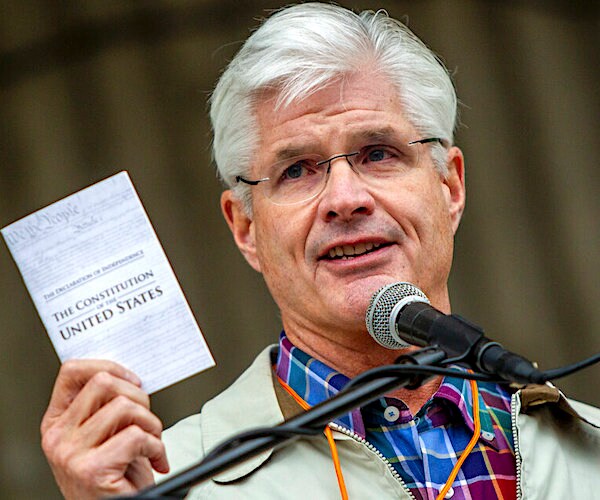 mike shirkey holds up a min constitution and smiles