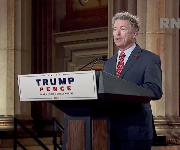 sen. rand paul speaks at a podium in an empty auditorium for the camera