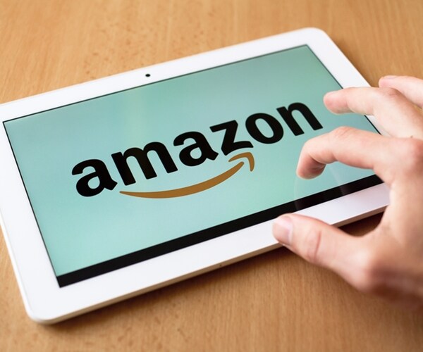 man's hand use with his fingers tablet. amazon app is on the screen.

