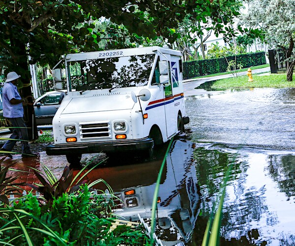 A postal worker returns to their truck parked on a flooded street a few miles from downtown Miami