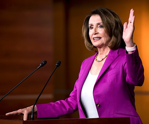 nancy pelosi raises her left hand as she delivers remarks at a news conference