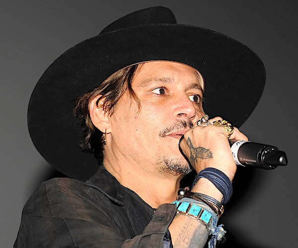 johnny depp speaks into a mic while wearing a top hat