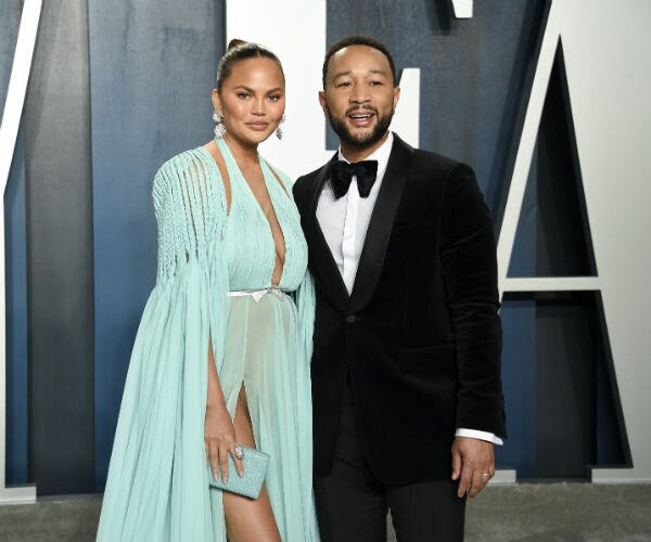 Chrissy Teigen, left, in a mint green evening gown and husband John Legend, in a tux,  arrive at an Oscar Party