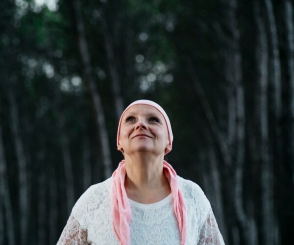 woman with scarf on head b/c of hair loss due to chemo looking up at sky