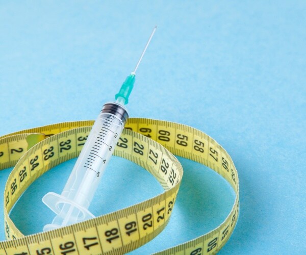 syringe of weight loss drug and measuring tape