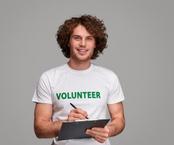 a young man with a volunteer t-shirt holds a clipboard