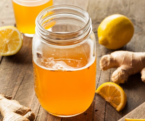 kombucha in a mason jar on table with pieces of ginger