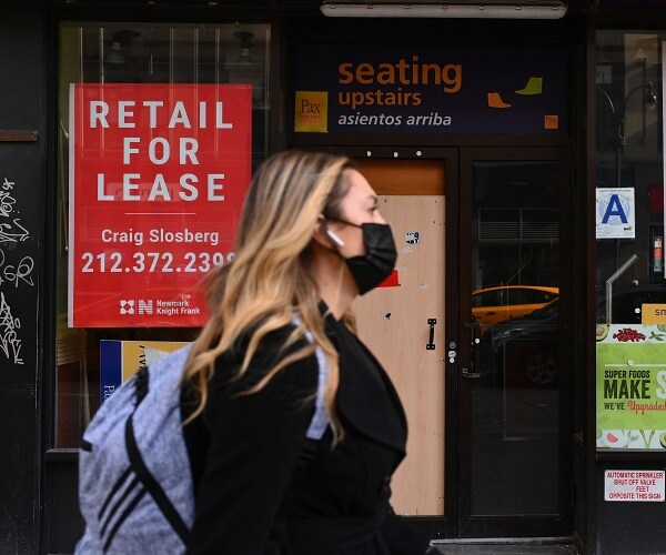 woman walks past closed store