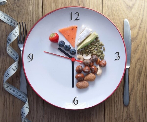 a plate with a clock, vegetables, fruits