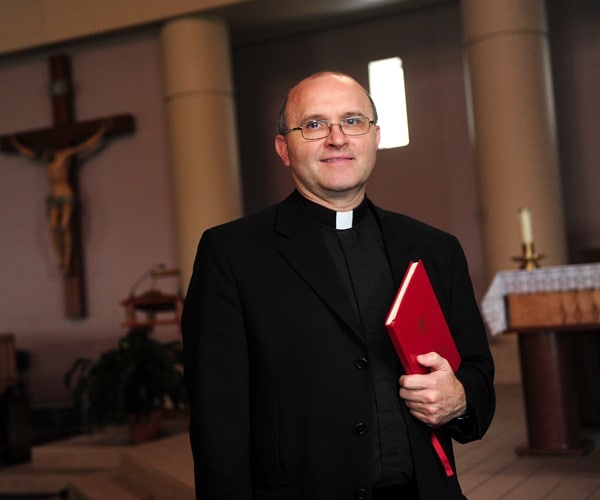 father vince lambert with the book he uses for exorcism