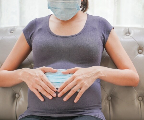 pregnant woman sitting in chair with mask on and mask on her stomach