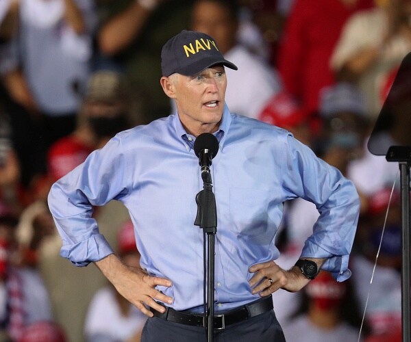 rick scott stands onstage with hands on hips