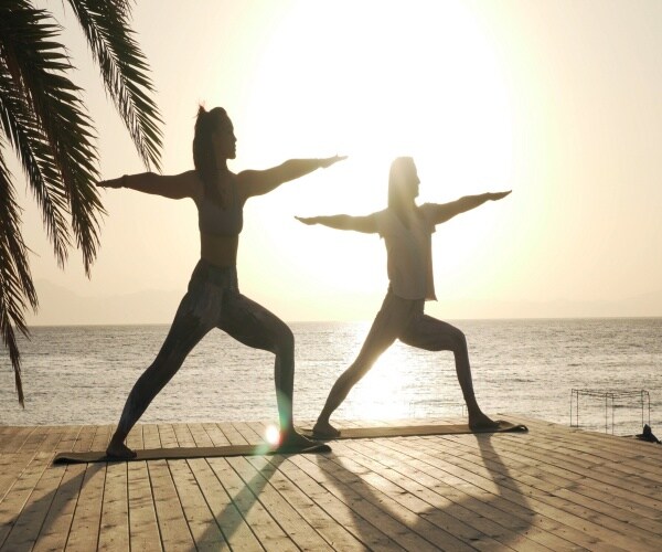 women doing yoga outside with sun in background