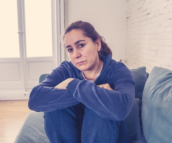 woman at home on couch looking lonely, sad