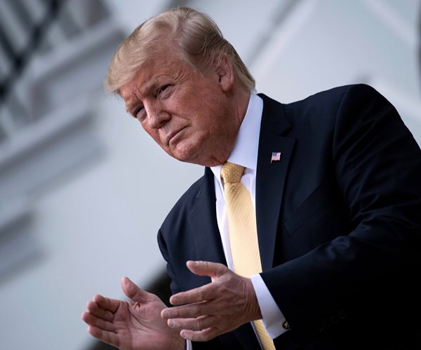 president donald trump applauds before speaking to the masses