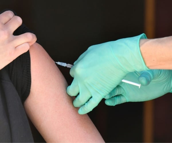 person in black t-shirt getting a vaccine