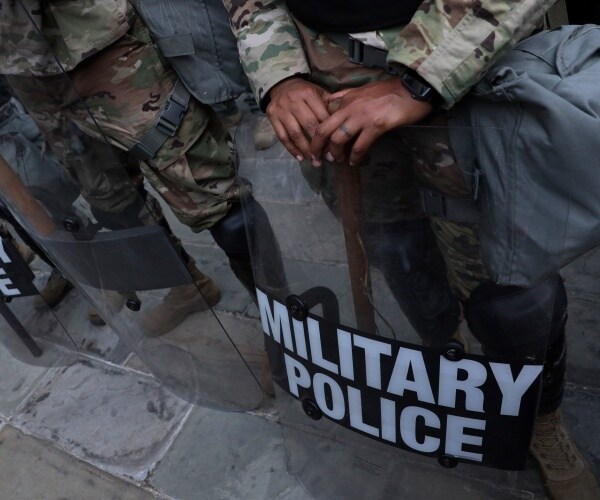 national guard members in uniforms and with shields labeled military police