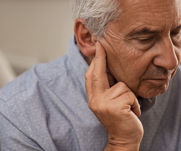 older man holds fingers to ear