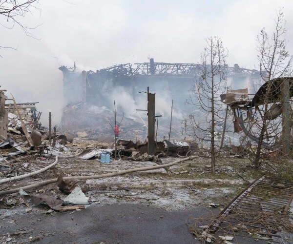 Firefighters spray water on a destroyed shoe factory