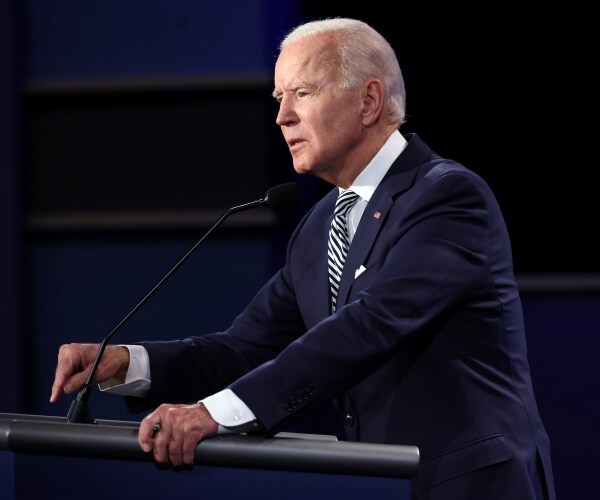 biden in a suit and black and white striped tie speaking at the debate