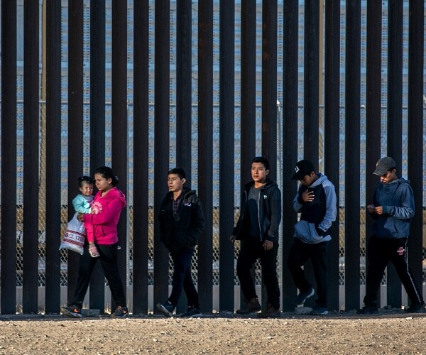 migrants walk along border fence