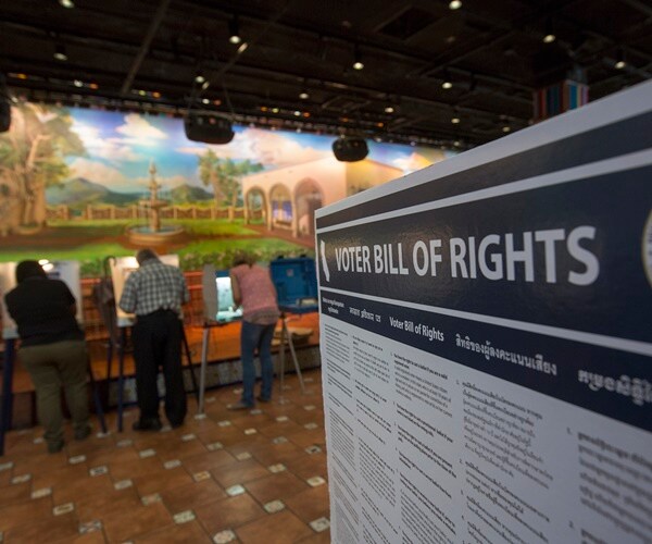 voter bill of rights sign at pollilng station with many latinos voting